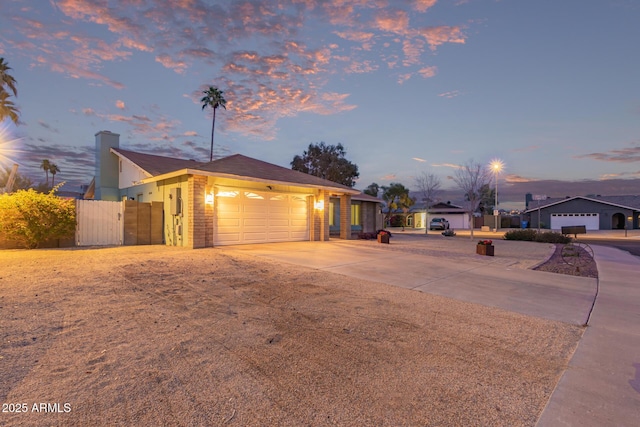 ranch-style house with a gate, fence, driveway, a chimney, and a garage