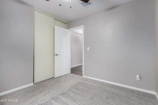 empty room with baseboards, visible vents, a ceiling fan, and carpet