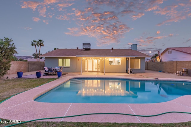 pool at dusk featuring central air condition unit, a patio area, a fenced in pool, and a fenced backyard