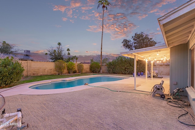 pool at dusk featuring a patio, a fenced backyard, and a fenced in pool