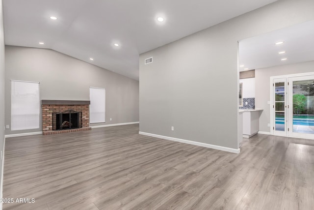 unfurnished living room featuring lofted ceiling, recessed lighting, baseboards, and light wood finished floors