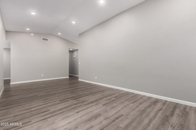 empty room featuring visible vents, baseboards, vaulted ceiling, recessed lighting, and wood finished floors