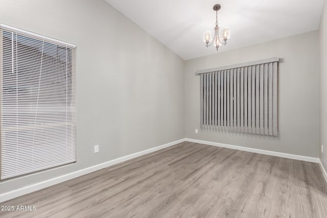 unfurnished room featuring wood finished floors, baseboards, and a chandelier