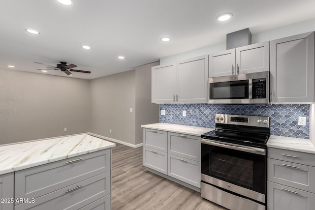 kitchen featuring a ceiling fan, light wood-style flooring, gray cabinetry, appliances with stainless steel finishes, and tasteful backsplash