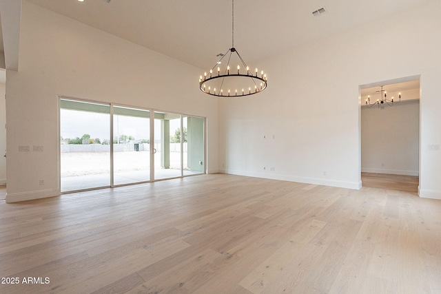 6832 N 178th Ln, Waddell, AZ 85355 - empty room featuring light wood-type flooring, visible vents, a notable chandelier, and a high ceiling