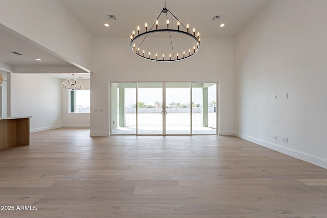 6832 N 178th Ln, Waddell, AZ 85355 - unfurnished living room with visible vents, baseboards, a chandelier, light wood-style floors, and a towering ceiling