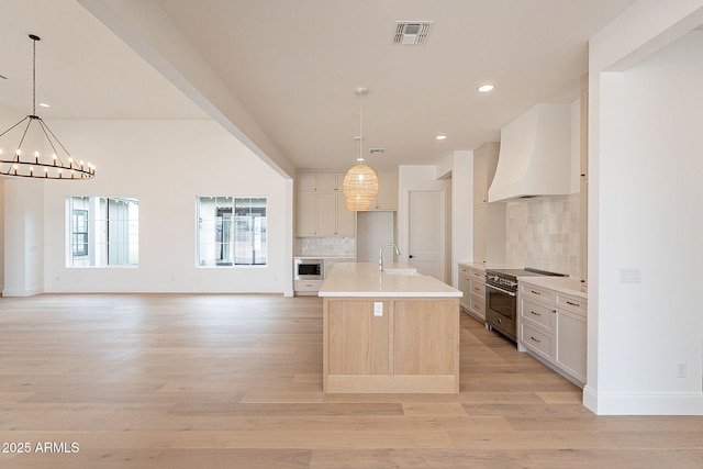 6832 N 178th Ln, Waddell, AZ 85355 - kitchen with premium range hood, visible vents, open floor plan, light wood-style floors, and appliances with stainless steel finishes