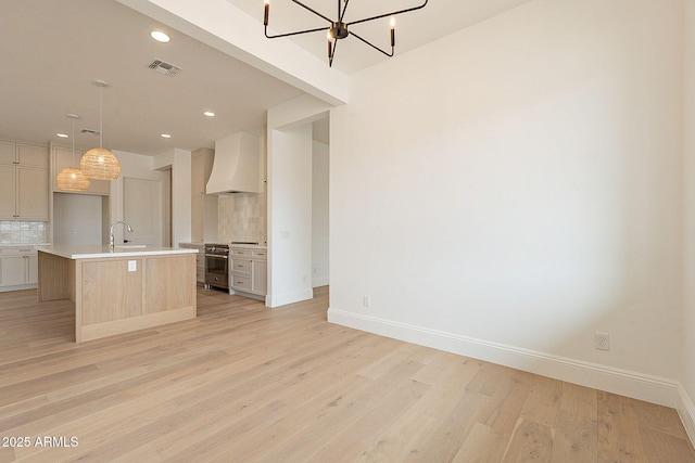 6832 N 178th Ln, Waddell, AZ 85355 - kitchen with premium range hood, light wood finished floors, tasteful backsplash, stainless steel stove, and light countertops
