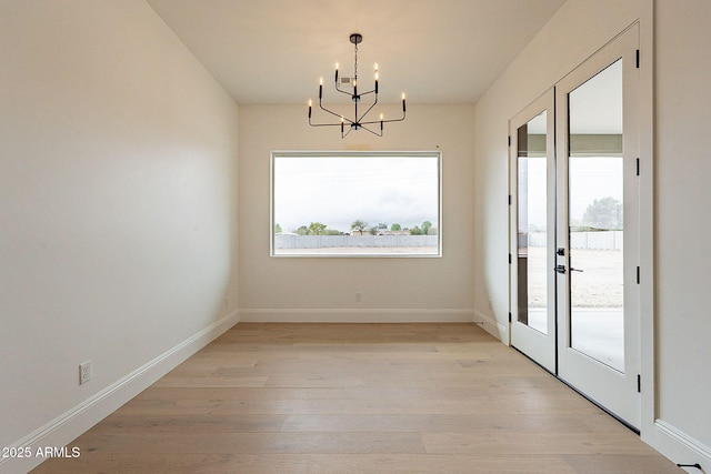 6832 N 178th Ln, Waddell, AZ 85355 - unfurnished dining area featuring a healthy amount of sunlight, baseboards, light wood-style flooring, and an inviting chandelier