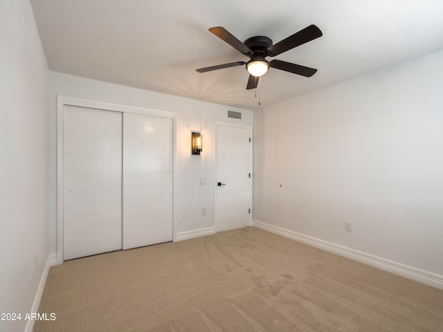 unfurnished bedroom featuring light carpet, ceiling fan, and a closet