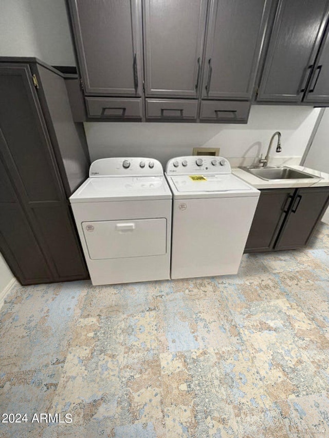 clothes washing area with cabinets, sink, and independent washer and dryer