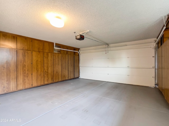 garage with wood walls and a garage door opener