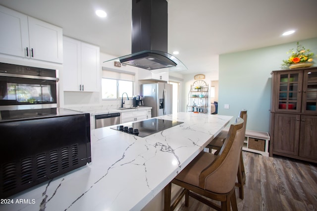 kitchen with light stone counters, dark wood-type flooring, white cabinetry, island exhaust hood, and appliances with stainless steel finishes