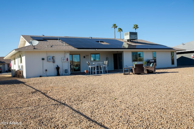 rear view of property featuring cooling unit, solar panels, and a patio area