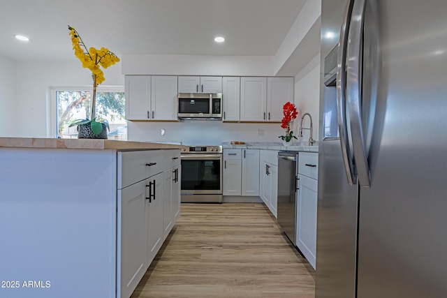 kitchen with light wood-style flooring, recessed lighting, appliances with stainless steel finishes, white cabinets, and light countertops