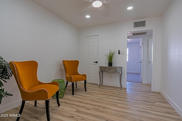 living area with ceiling fan and light hardwood / wood-style floors