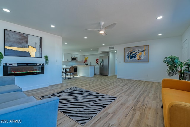 living room featuring ceiling fan and light hardwood / wood-style floors