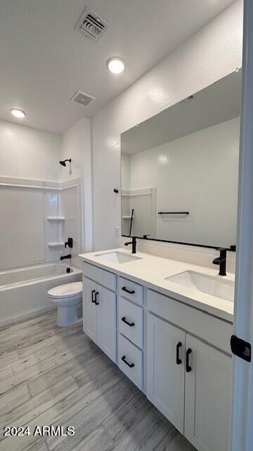 full bathroom with shower / tub combination, vanity, toilet, and hardwood / wood-style floors