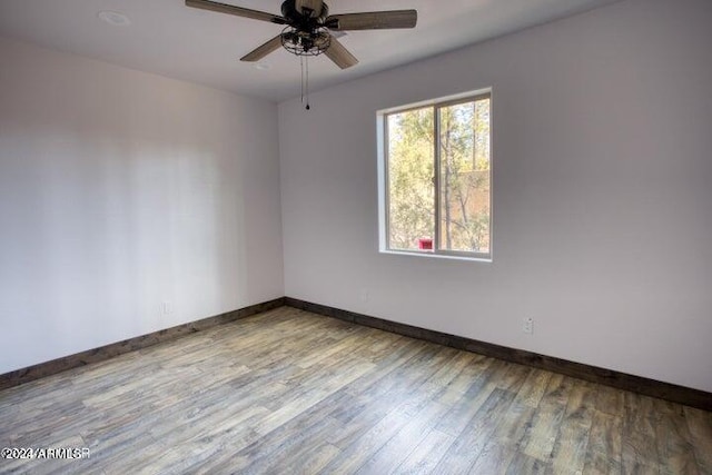 spare room with a ceiling fan, baseboards, and wood finished floors