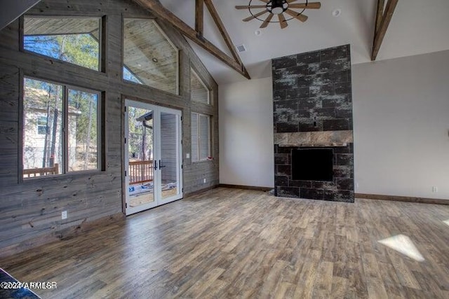 unfurnished living room with hardwood / wood-style flooring, ceiling fan, beam ceiling, high vaulted ceiling, and a fireplace