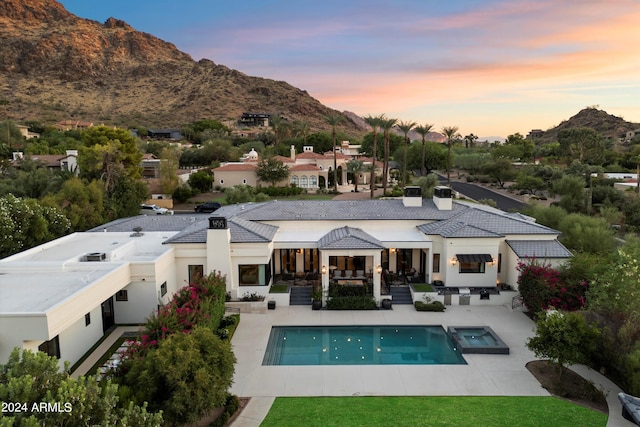 back house at dusk with a mountain view and a patio