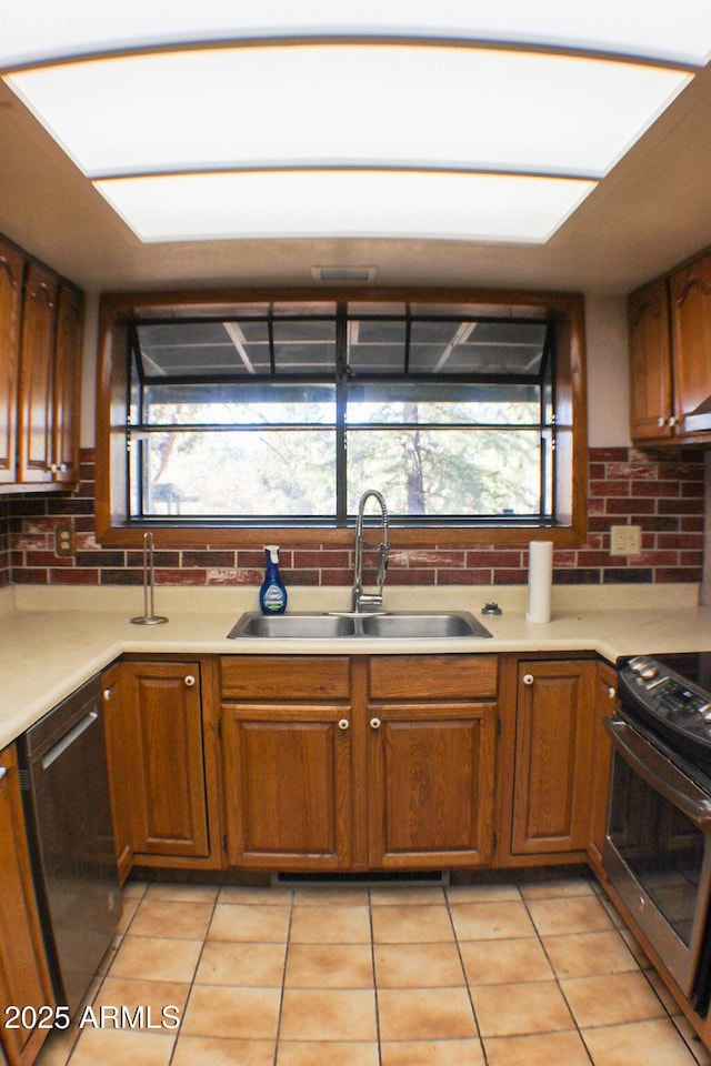 kitchen featuring dishwasher, sink, light tile patterned flooring, and stainless steel stove