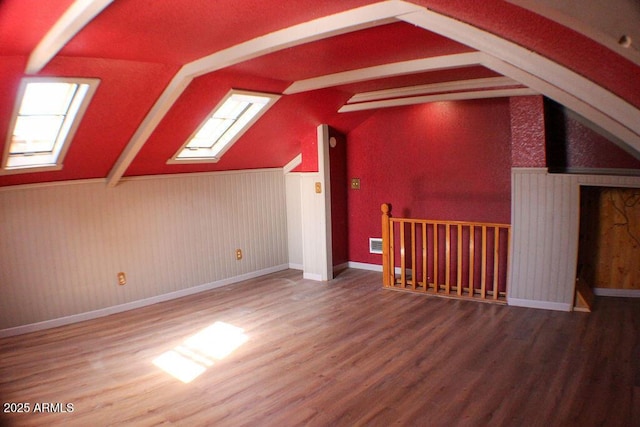 additional living space featuring hardwood / wood-style flooring and lofted ceiling with skylight