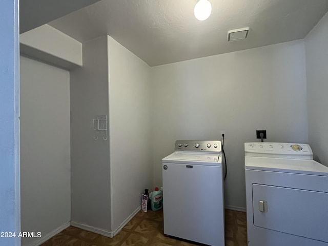 washroom with dark parquet flooring and washing machine and clothes dryer