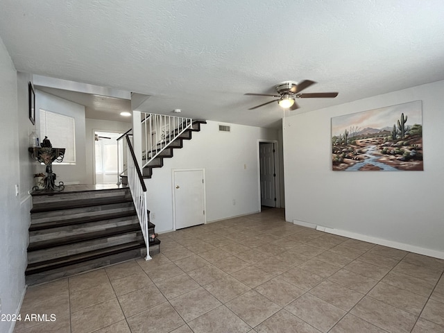 interior space with ceiling fan, light tile patterned floors, and a textured ceiling