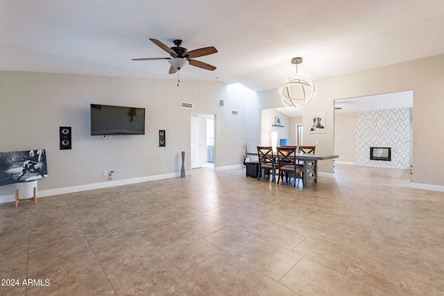 dining space with ceiling fan, lofted ceiling, and a tiled fireplace