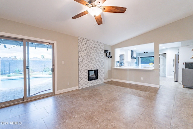 unfurnished living room with ceiling fan, a fireplace, lofted ceiling, and sink