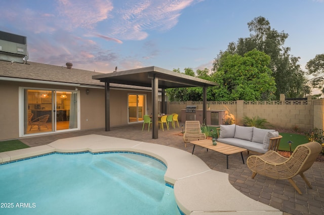 pool at dusk with a patio, an outdoor kitchen, an outdoor hangout area, and area for grilling