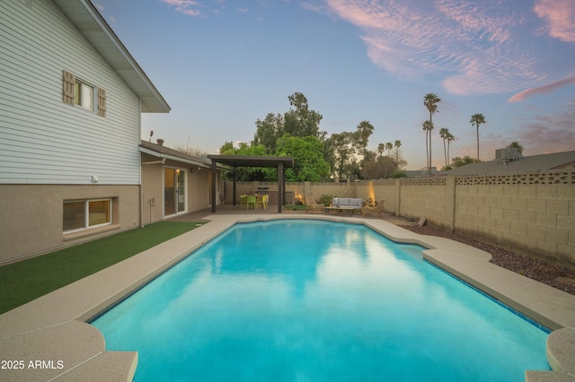 pool at dusk featuring an outdoor living space and a patio area