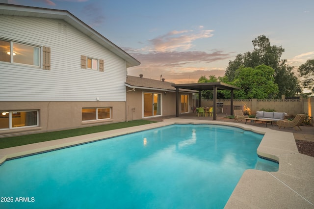 pool at dusk featuring an outdoor hangout area and a patio