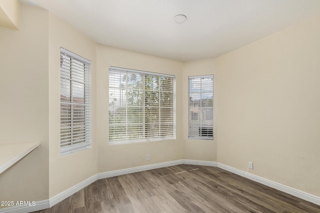 spare room with baseboards and wood finished floors