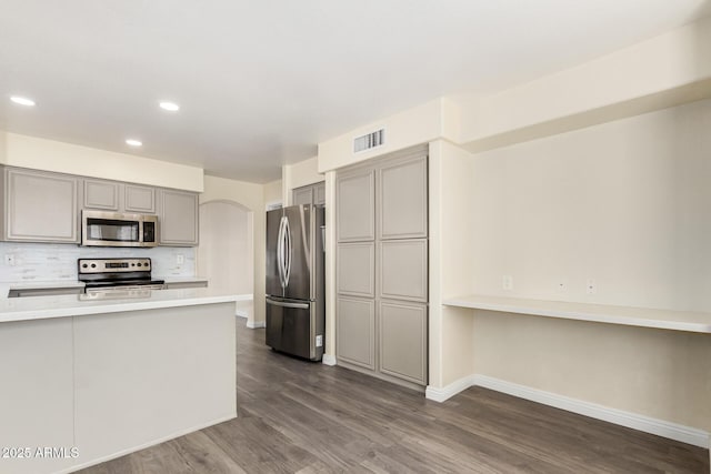 kitchen with decorative backsplash, visible vents, stainless steel appliances, dark wood-type flooring, and gray cabinets