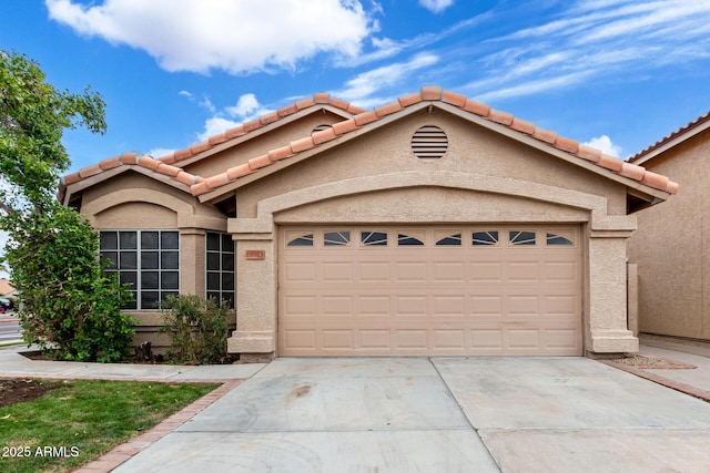 view of front of property featuring a tiled roof, concrete driveway, stucco siding, and an attached garage