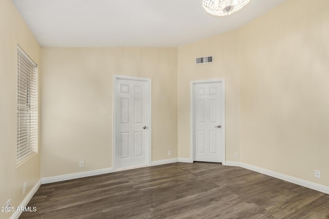 unfurnished bedroom with dark wood finished floors, baseboards, and visible vents
