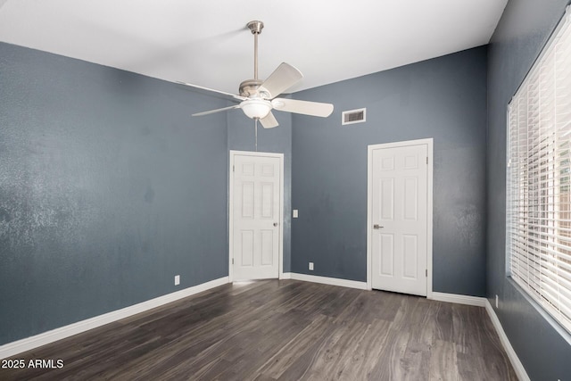 spare room featuring a ceiling fan, dark wood-style floors, baseboards, and visible vents