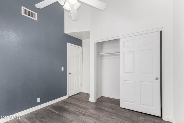 unfurnished bedroom featuring a closet, visible vents, baseboards, ceiling fan, and dark wood-style floors