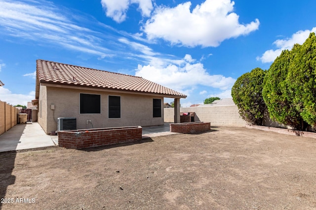 rear view of house with cooling unit, a fenced backyard, a tiled roof, and a patio area