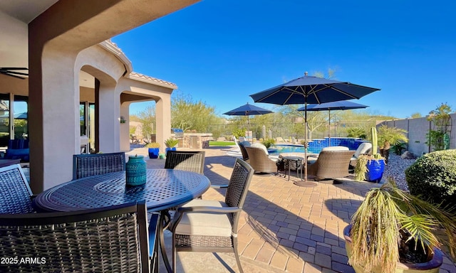 view of patio with outdoor dining space, an outdoor pool, and fence