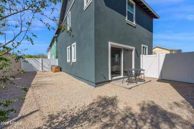 rear view of property with a patio area, stucco siding, a fenced backyard, and a gate
