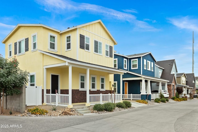 view of front of home featuring covered porch, board and batten siding, stone siding, and a residential view