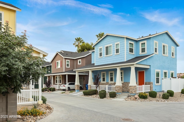 view of front of house featuring a porch, stone siding, stucco siding, and fence