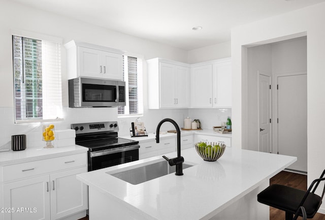 kitchen featuring appliances with stainless steel finishes, a sink, tasteful backsplash, a breakfast bar area, and recessed lighting