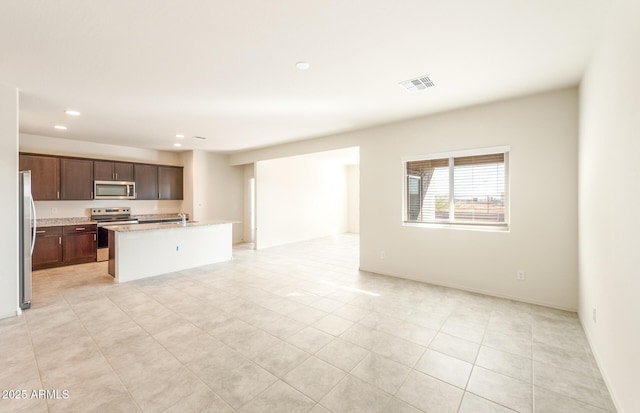 5029 S 252nd Ave, Buckeye, AZ 85326 - kitchen featuring appliances with stainless steel finishes, open floor plan, recessed lighting, a kitchen island with sink, and light tile patterned flooring