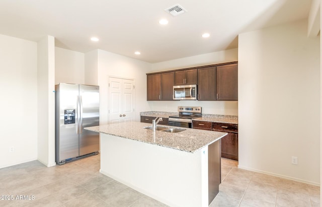 5029 S 252nd Ave, Buckeye, AZ 85326 - kitchen featuring stainless steel appliances, a sink, an island with sink, dark brown cabinets, and light stone countertops