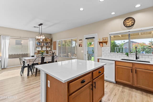 kitchen featuring dishwasher, a center island, sink, light hardwood / wood-style flooring, and pendant lighting