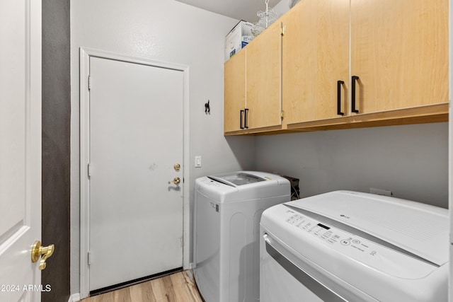 washroom featuring washer and clothes dryer, cabinets, and light hardwood / wood-style floors